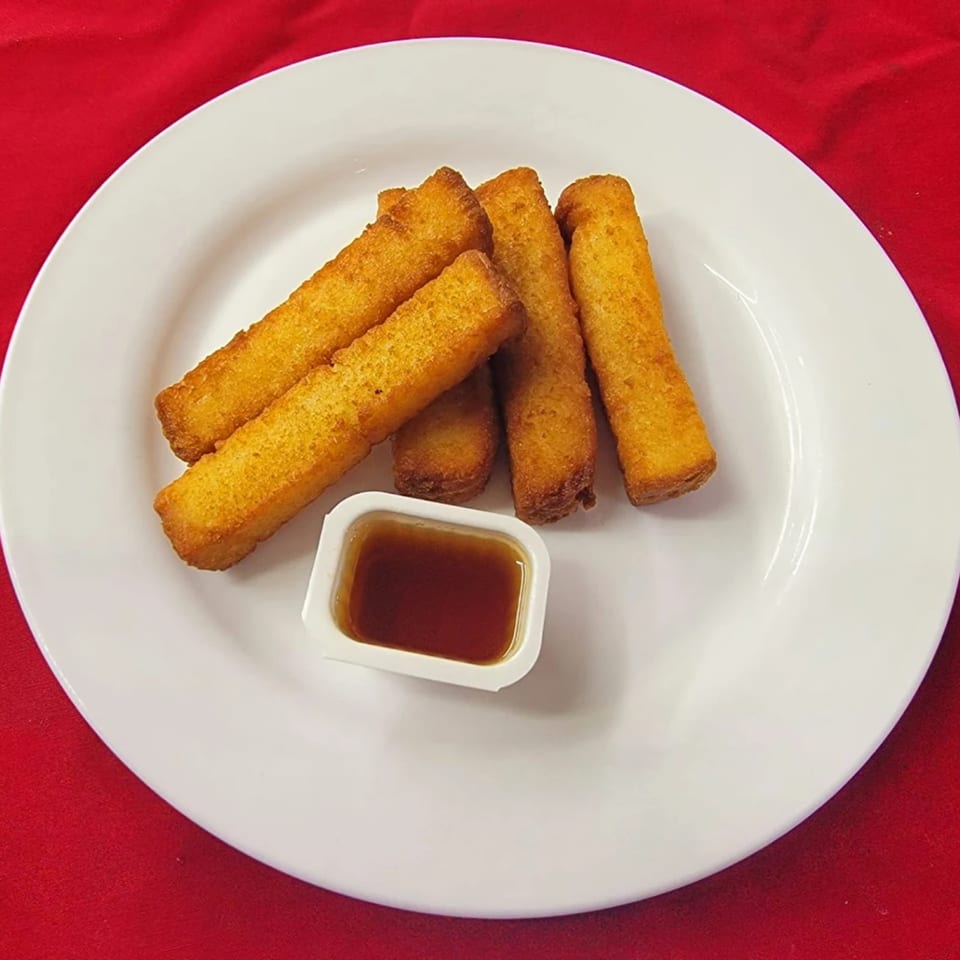 Golden-brown fish sticks and a small container of dipping sauce on a white plate.