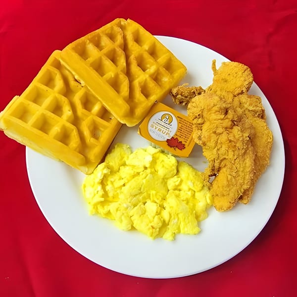 Hook Fish and Chicken's breakfast plate with waffles, scrambled eggs, fried chicken, and syrup.