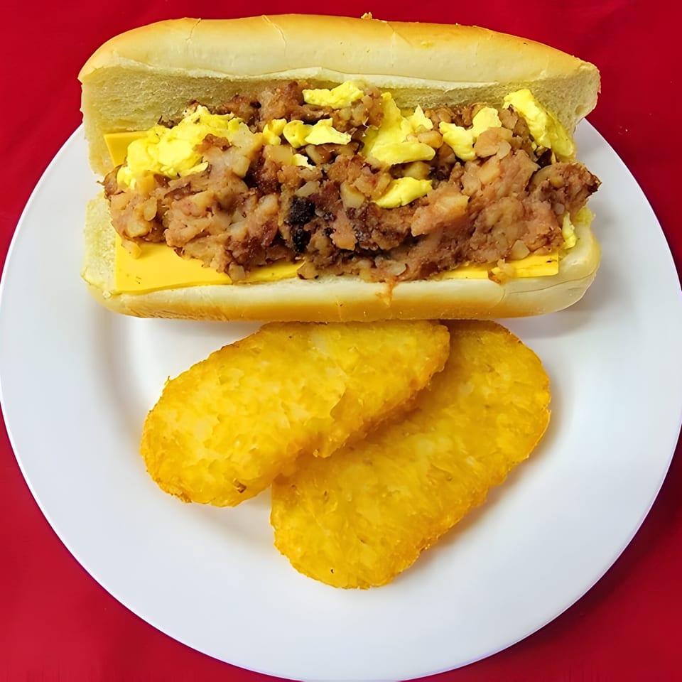 A breakfast sandwich with scrambled eggs, hash, and cheese, served with two hash browns.